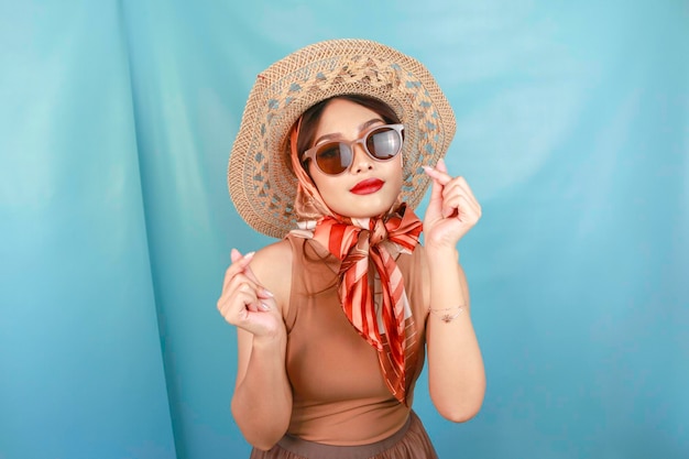 Traveling concept of a young Asian happy woman showing love or mini heart isolated by a blue background