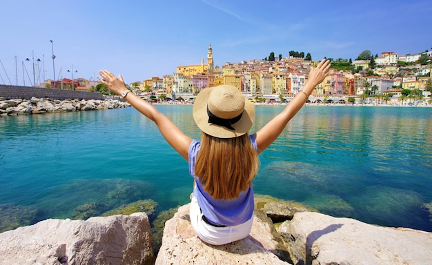 Traveling in France Panoramic view of traveler girl with arms raised enjoying view of Menton village French Riviera