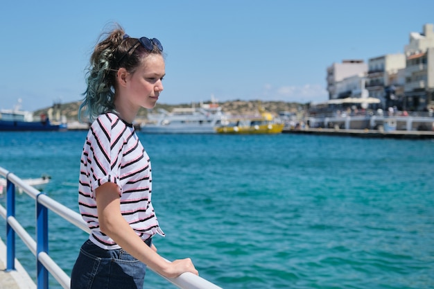 Traveling teenager girl on sea bay enjoys beauty nature, summer holidays on sea voyage