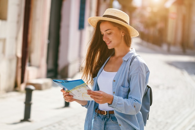 ヨーロッパに沿って旅行中に旅行マップで正しい方向を検索する帽子の旅行女性。休暇と旅行のライフスタイル