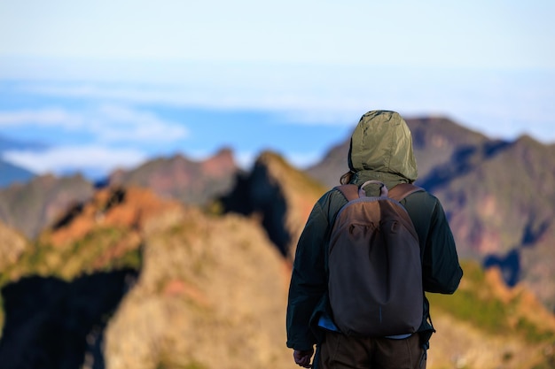 Путешествующая женщина, стоящая на вершине горы и наблюдающая за прекрасным видом на величественные горы