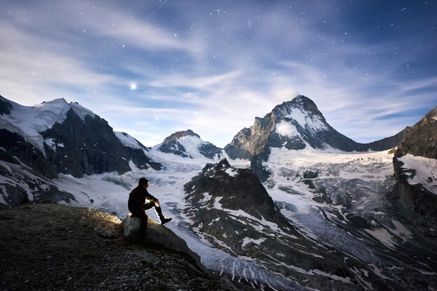 Viaggiatore che si gode un'incredibile notte stellata in montagna nelle alpi svizzere