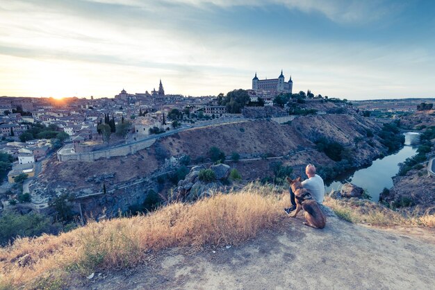 Photo traveller man and dog watching toledo cityscape from hill