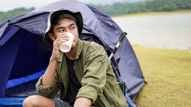 旅行者の男はキャンプでコーヒーを飲む