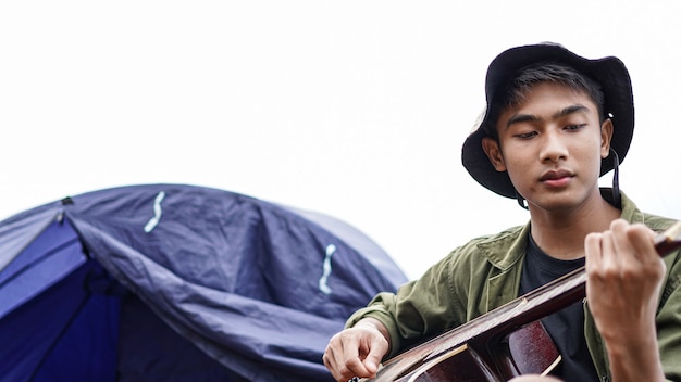 Traveller man playing guitar at camp