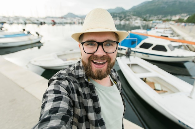 晴れた日の旅行と夏のコンセプトの間に海の豪華ヨットのselfieを取る旅行者の男