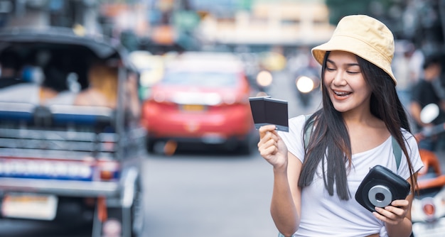 Traveller woman holding instant camera and film at Khao San road, Bangkok city of Thailand. 