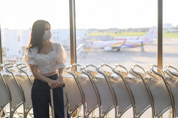 A traveller woman is wearing protective mask in International airport, travel under Covid-19 pandemic, safety travels, social distancing protocol