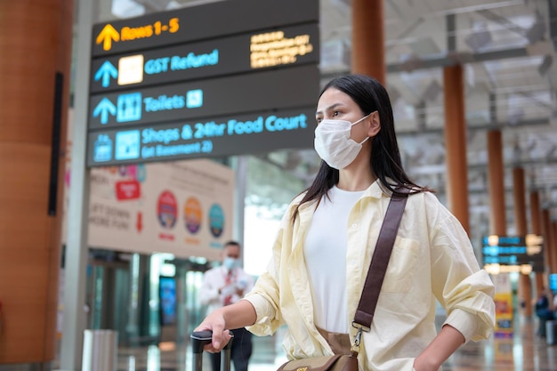 旅行者の女性が国際空港で保護マスクを着用しています