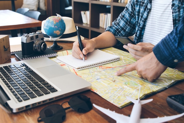 Travelling concept.Two men choosing place of vacation, exploring compromise on map, taking notes in notebook