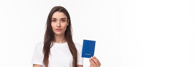 Travelling holidays summer concept seriouslooking young confident girl showing her brand new passpor