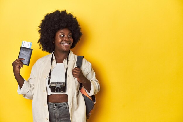 Photo travelready africanamerican woman holding an airplane ticket on a yellow background