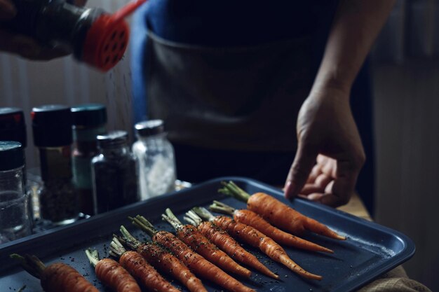 A tray of carrots on a counter with seasonings on it.