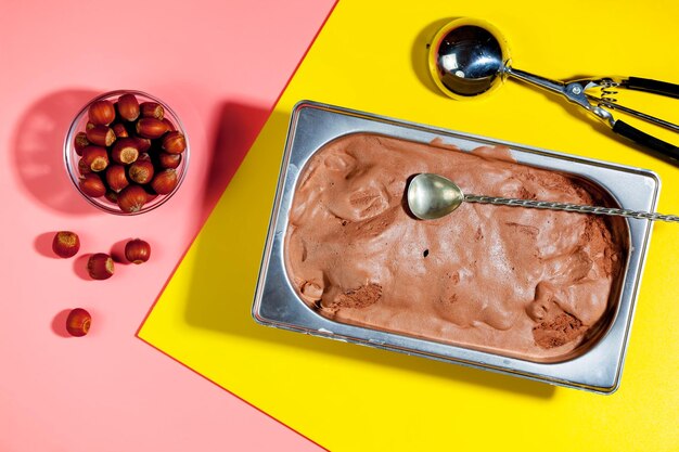 A tray of chocolate ice cream with a spoon on top of it and a bowl of cranberries on the side.