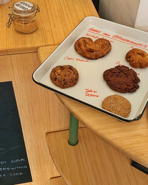 A tray of different kinds of cookies on a table with a chalkboard that says