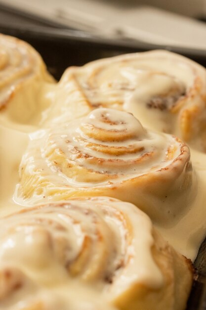 Tray of freshly baked cinnamon rolls with icing closeup of cinnamon rolls with icing vertical ima