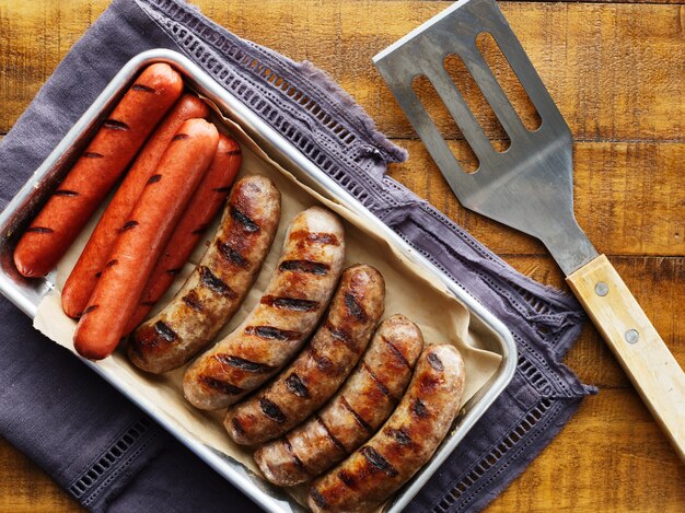 Photo tray of grilled hot dogs and bratwursts on tray in top down composition