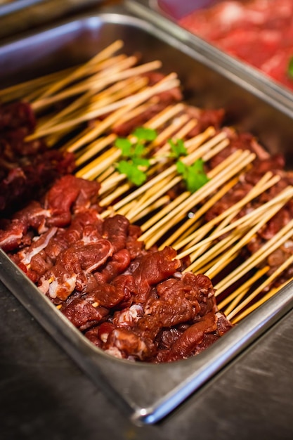 A tray of meat on sticks with a green leaf on top