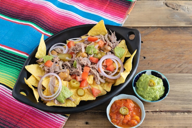 Tray of nachos with meat and mexican decoration Bowls with salsa Top view Copy space