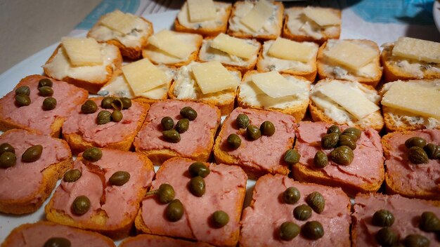 A tray of sandwiches with meats, cheese, and olives