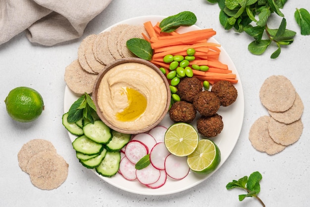 Foto piatto servito con hummus, salsa, falafel, radice, cetriolo, carote, bastoncini, cracker