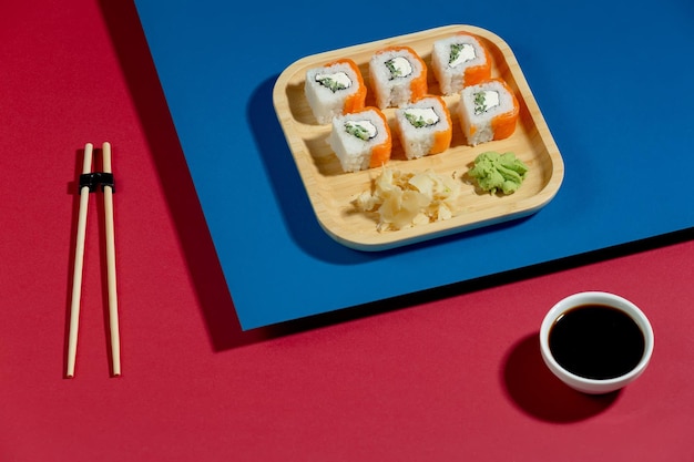 A tray of sushi with sushi on it and a cup of soy sauce on the table.