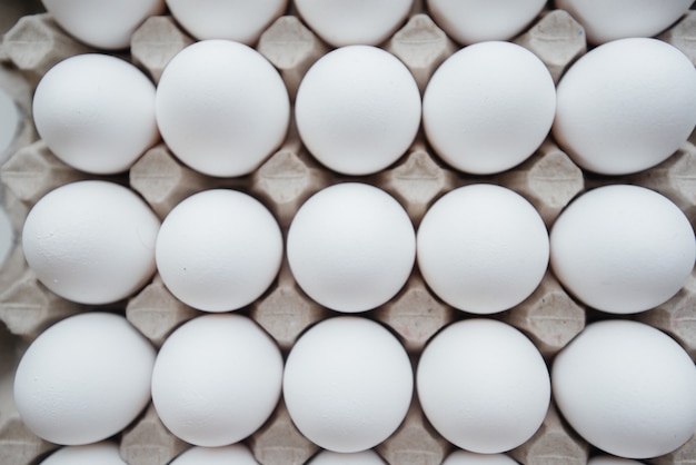 Tray of white fresh eggs close-up on a cardboard form. Agricultural industry