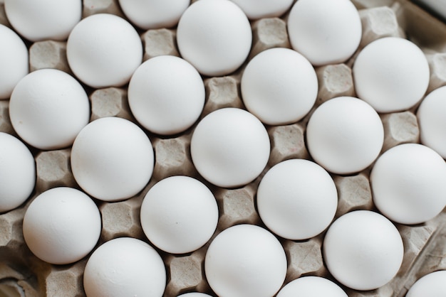 Tray of white fresh eggs close-up on a cardboard form. Agricultural industry