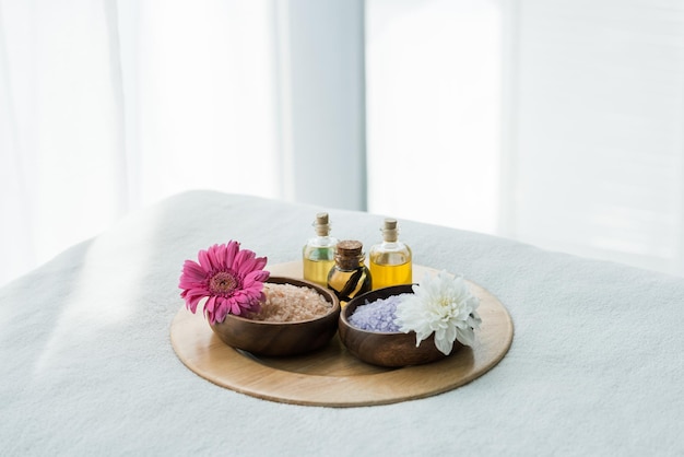 Tray with bottles of oil wooden bowls with sea salt and flowers in spa center