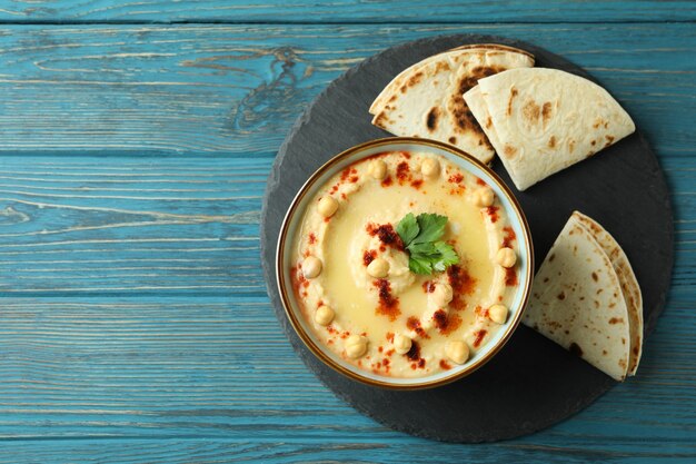 Tray with bowl of hummus and pita on wooden wall