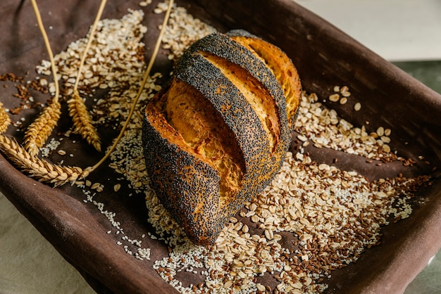 Foto vassoio con pane, semi e spighe di grano