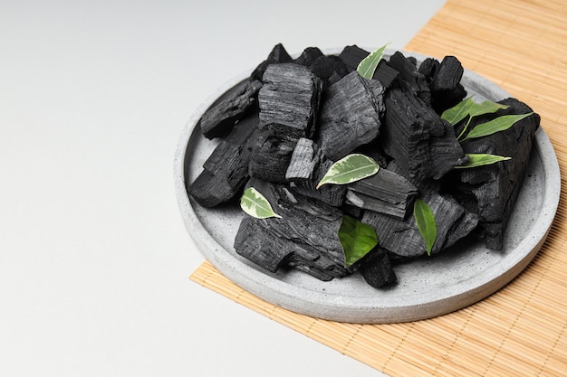 Tray with charcoal and leaves on bamboo mat