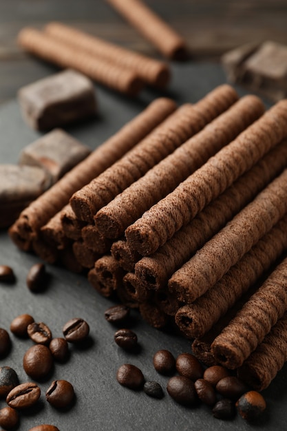 Tray with chocolate wafer rolls, coffee beans and chocolate, close up