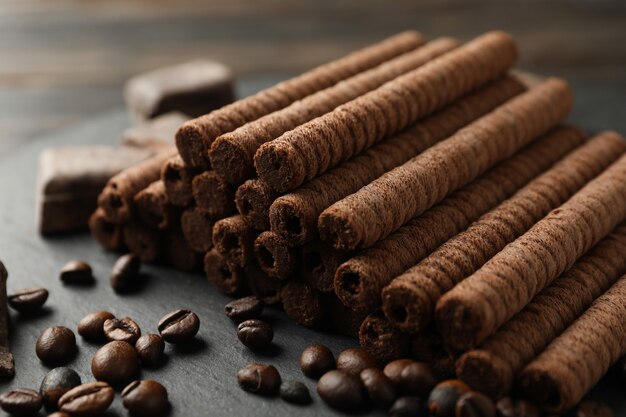 Tray with chocolate wafer rolls, coffee beans and chocolate, close up