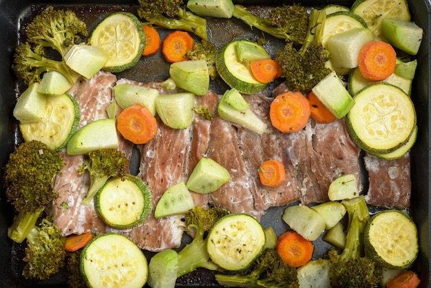 Tray with fish fillets and vegetables baked on a wooden table Healthy food