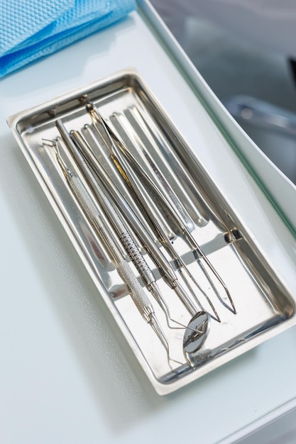 Фото Поднос с металлическими стоматологическими инструментами инструменты стоматолога интерьер приемной пациента с стоматологическим оборудованием в стоматологической клинике