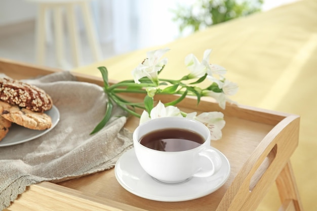 Tray with tasty breakfast and flowers on bed closeup