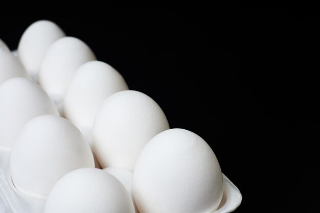 Tray with white chicken eggs on a dark background