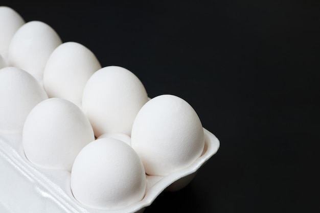 Tray with white chicken eggs on a dark background