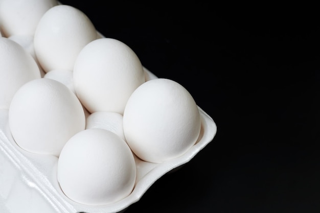 tray with white chicken eggs on a dark background