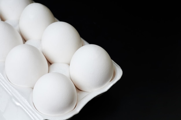 Tray with white chicken eggs on a dark background