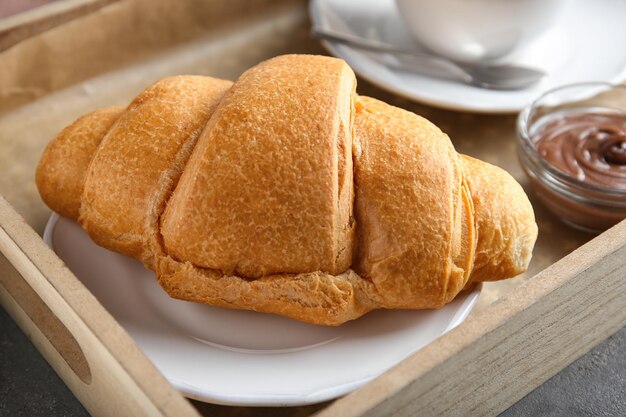 Tray with yummy croissant on table closeup