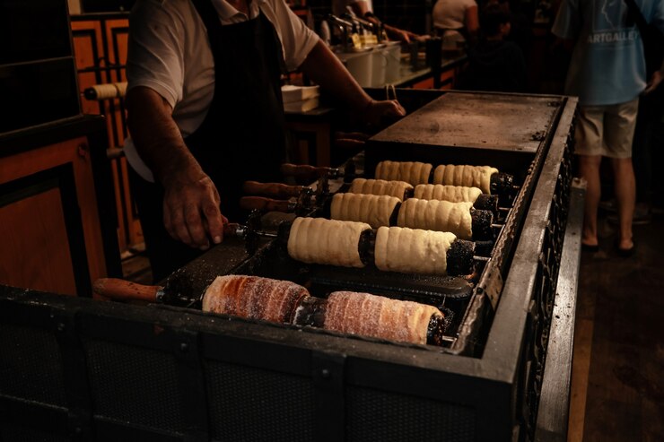 프라하의 거리 시장에 있는 Trdelnik 빵집. 확대. 길거리 음식. Trdelnik은 화덕에서 조리한 달콤한 반죽의 튜브입니다. 선택적 초점입니다.
