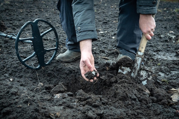 A treasure hunter digs up an old coin with a shovel in the field Metal detector and shovel or ground treasure hunting equipment Fortune during the antiques hunt