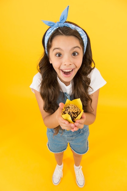 Treat someone with sweets yummy cupcake homemade muffin sweet tooth concept kid girl hold appetizing muffin gluten free recipe delicious cupcake little child with muffin on yellow background