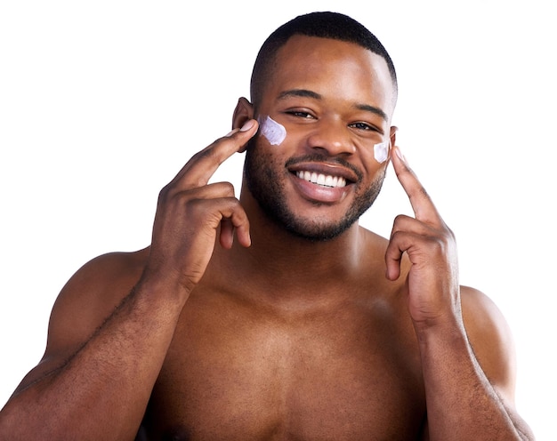 Treating my skin Studio portrait of a handsome young man moisturizing his face against a white background