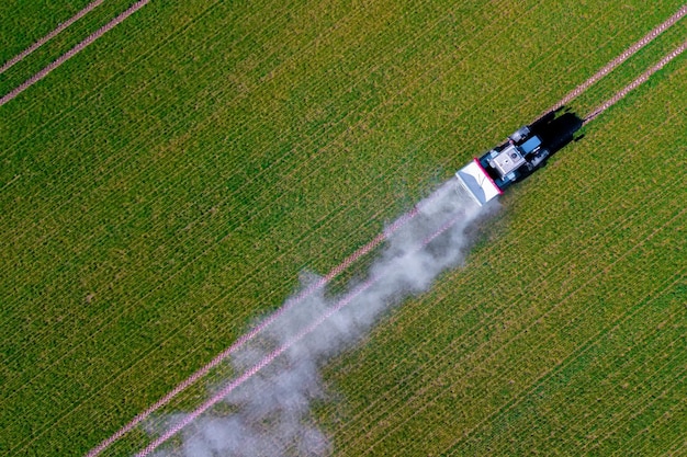 Treatment of fields with pestecides agriculture tractor rides\
on the field top view