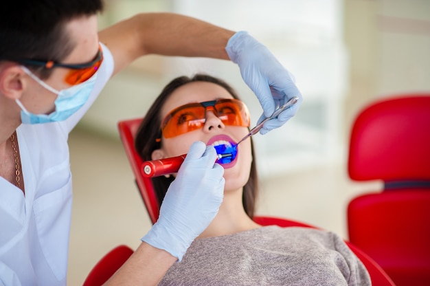 Trattamento della bella ragazza di tenuta leggera in odontoiatria.