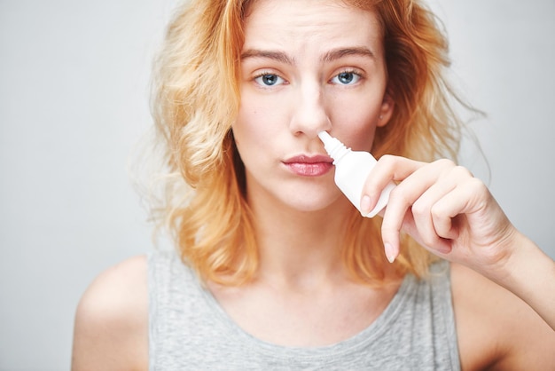 Photo the treatment of rhinitis. girl dripping nose drops