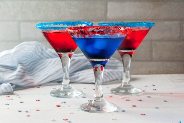 Удовольствия к празднику Дня независимости 4 июля. Удар по домашним алкогольным коктейлям в традиционных цветах - красный, синий, белый, со льдом. На домашнем кухонном столе.
